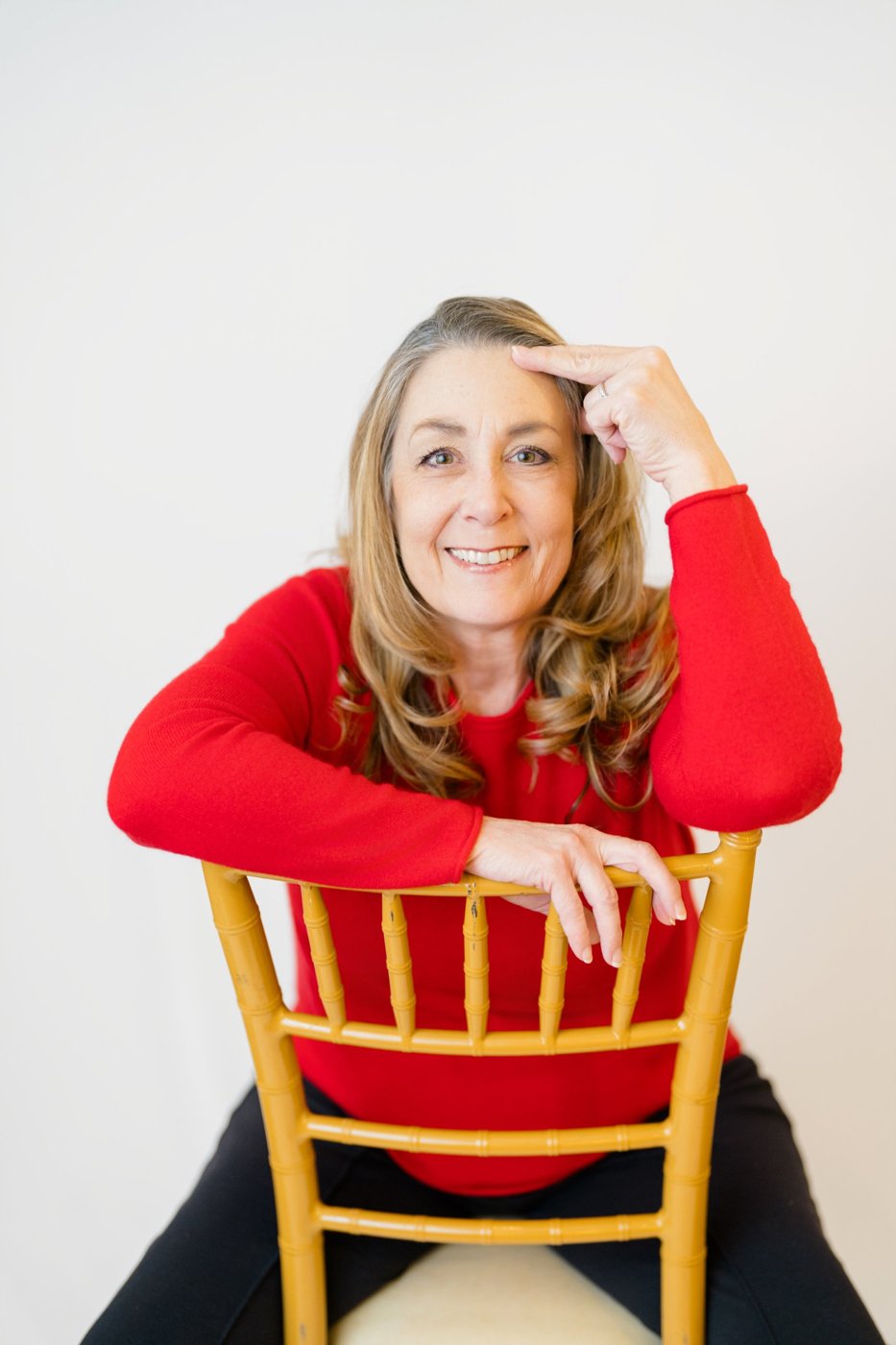 Tracy Goodwin leaning on a gold chair, smiling