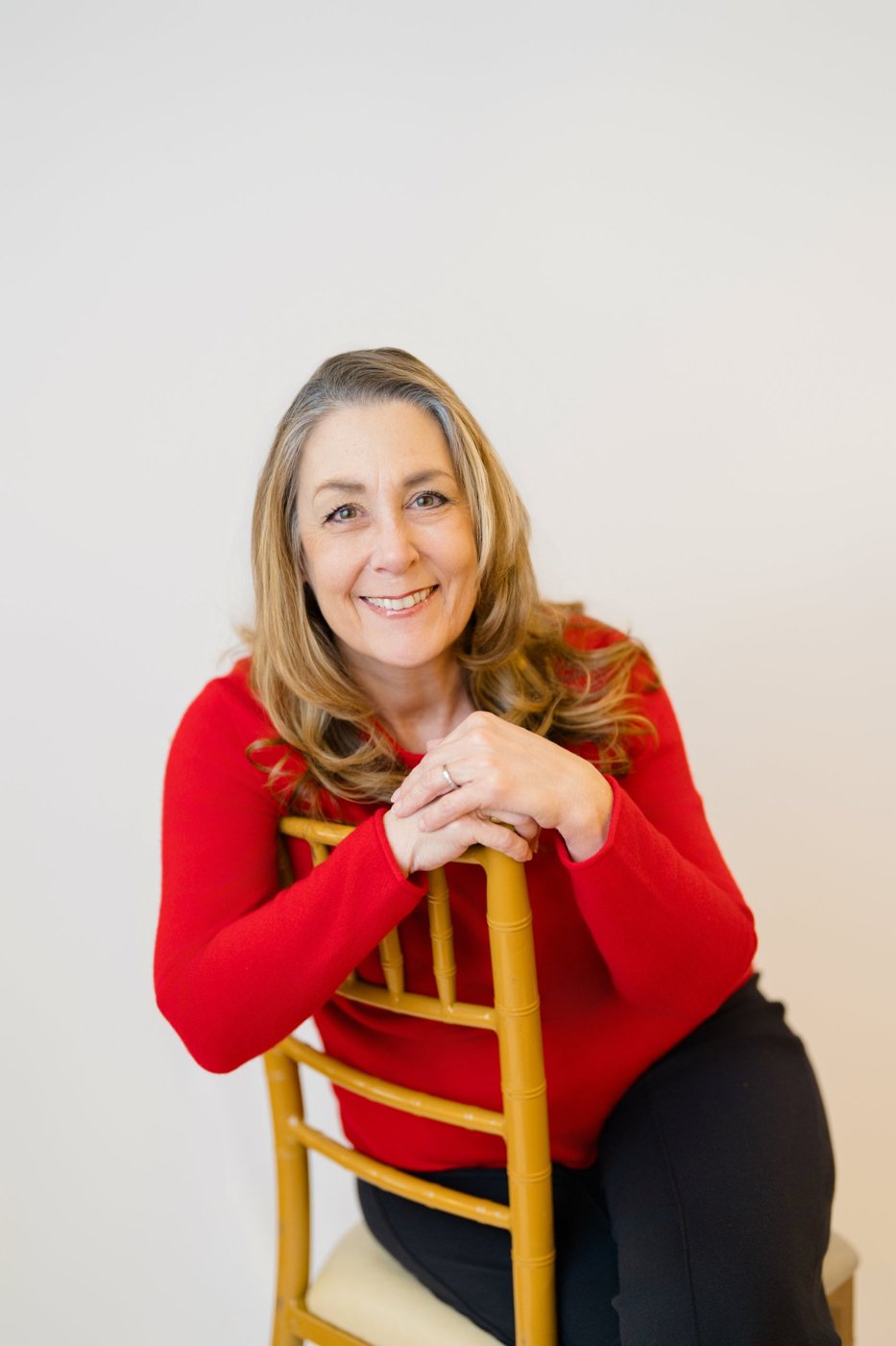 Tracy Goodwin seated on a gold chair, smiling